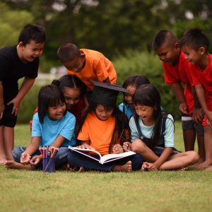 group of children lying reading on grass field