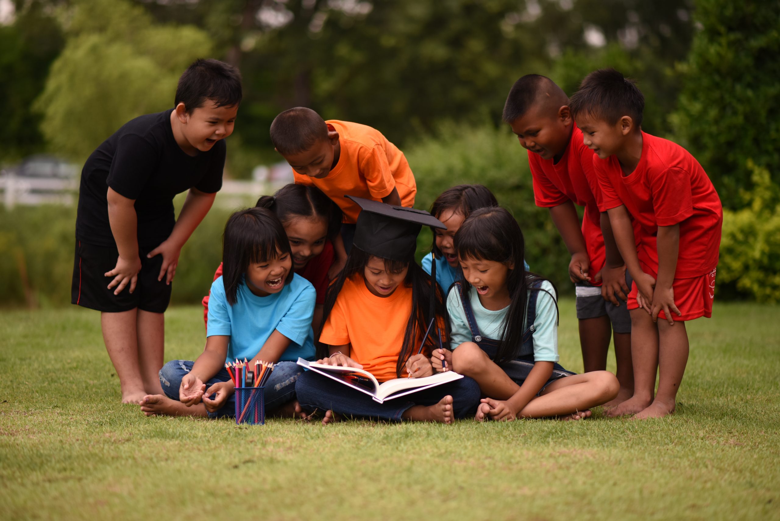 group of children lying reading on grass field